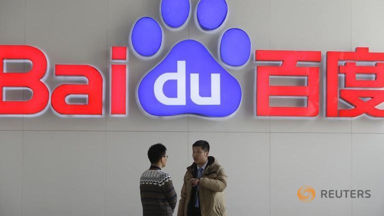 People talk in front of a Baidu's company logo at Baidu's headquarters in Beijing