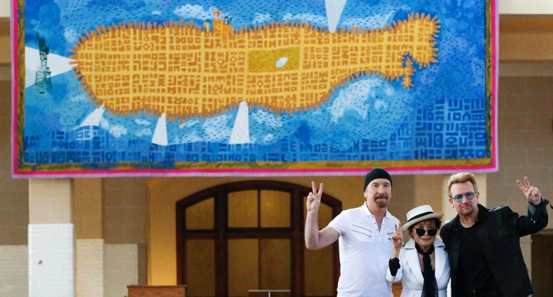 Artist Yoko Ono, widow of John Lennon poses with Irish singer Bono and guitarist The Edge of U2 during the unveiling of a tapestry honoring Lennon at Ellis Island in New York