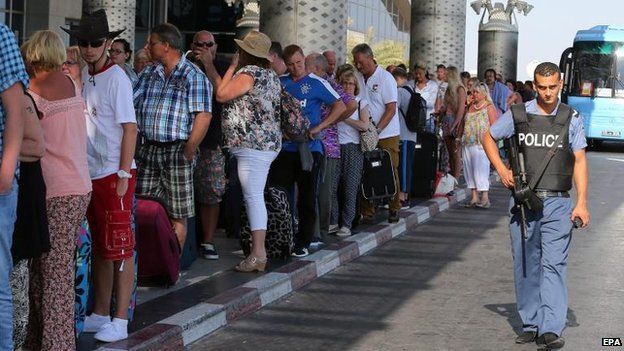 A Tunisian policeman stands guard in front of British tourists at the Enfidha International airport in Sousse Tunisia