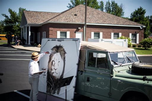 Artist Mark Balma paints a mural of Cecil a well-known lion killed by Minnesota dentist Walter Palmer during a guided bow hunting trip in Zimbabwe as part of a silent protest outside Palmer's office in Bloomington Minn. Wednesday