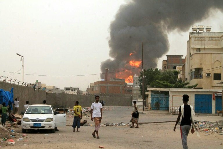 Yemenis watch as smoke billows following clashes between fighters loyal to exiled President Hadi and Huthi rebels in Aden