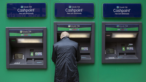 A customer uses an ATM outside a Lloyds bank branch