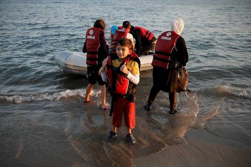 A migrant boy removes his lifejacket moments after arriving on a dinghy with his family on the Greek island of Kos