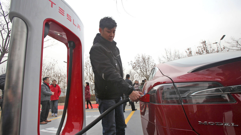 A staff member recharges a Tesla Model S electric car at a supercharger station in Tianjin Cina 24 January