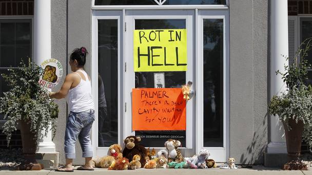 A woman moves a sign outside Dr Walter James Palmer's dental office in Bloomington Minnesota