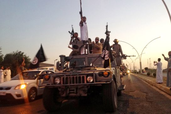 ISIS fighters parade through Mosul in a commandeered Iraqi military jeep in a 2014