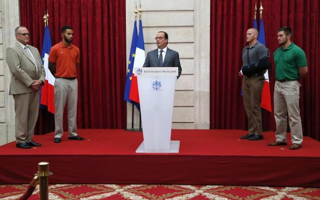 French President Francois Hollande delivers a speech as British businessman Chris Norman, US student Anthony Sadler, US Airman First Class Spencer Stone and US National Guardsman Alek Skarlatos listen to during a ceremony at the