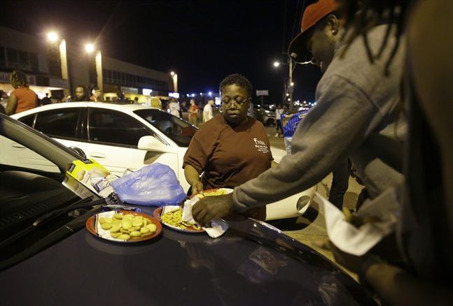 Cat Daniels puts out snacks as smaller group of protesters gather along West Florissant Avenue in Ferguson Mo. Tuesday Aug. 11 2015. The St. Louis suburb has seen demonstrations for days marking the anniversary of the death of 18-year-old Michael Brow