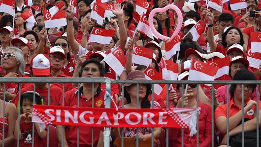 People wave national flags during Singapore's 50th National day anniversary celebration at the Padang in Singapore