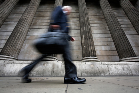 A pedestrian walks past stone columns outside the Bank of England in the City of London U.K. on Wednesday Aug. 5 2015