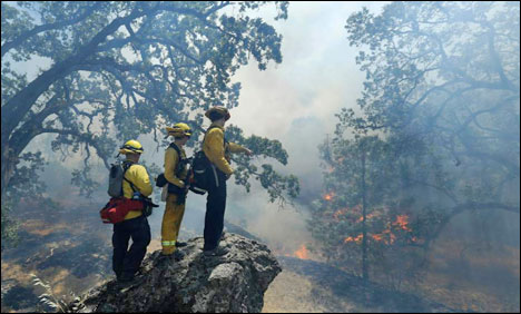 Garden Valley firefighter Chris Schwegler walks by flames along Morgan Valley Road near Lower Lake Calif. Thursday Aug. 13 2015. Crews battling the wind-stoked blaze took advantage of cooler temperatures Thursday to clear brush and expand containment