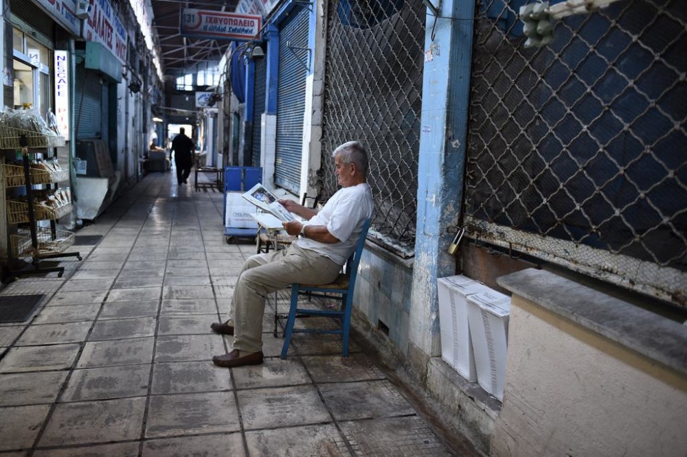 A man reads a newspaper outside a shop in in the northern Greek port city of Thessaloniki Tuesday Aug. 11 2015. Greece has agreed on the broad terms of a new three-year bailout package with international creditors with only a few details left to iron