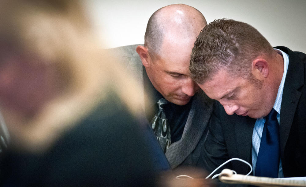 Former Albuquerque Police detective Keith Sandy left and police officer Dominique Perez right chat quietly during their preliminary hearing at the Bernalillo County District Courthouse in Albuquerque N.M. Thursday