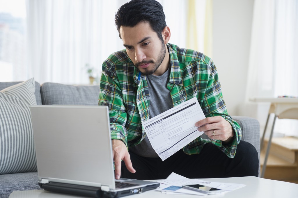 Mixed race man paying bills in living room