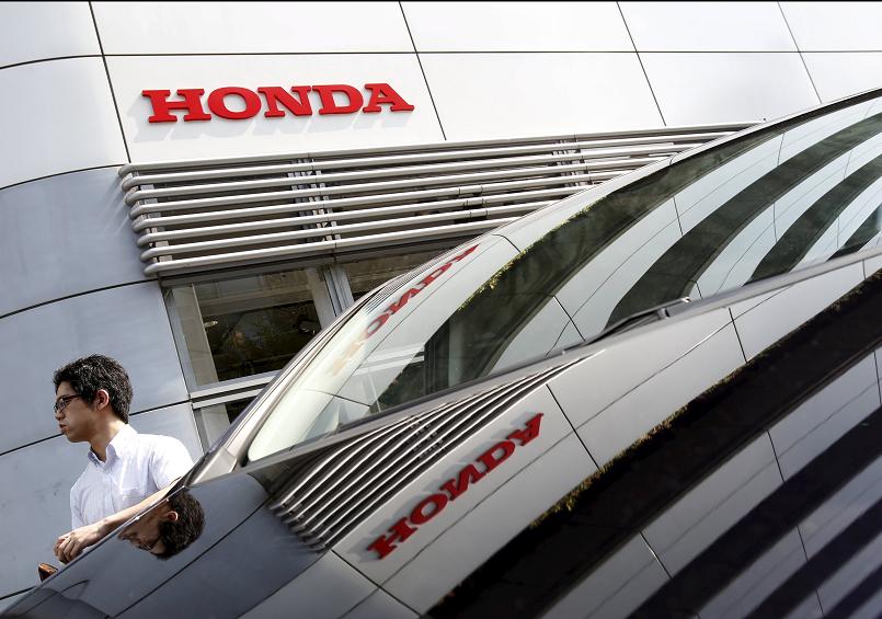 A man walks past a Honda Motor Co's car displayed outside a showroom at the company's headquarters in Tokyo Japan. Honda Motor Co says its quarterly net profit grew 20% as strong sales in North America its biggest market and a weak yen helped it absor