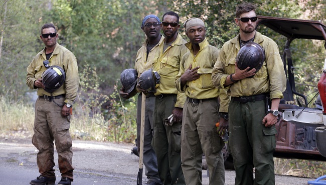 Jackson Hotshots&#039 firefighters from Jackson Miss stand with hands and helmets over their hearts as they watch a motorcade carrying the bodies of firefighters killed a day earlier while fighting a wildfire drive past