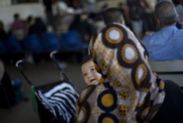 A Palestinian woman carries her child as she