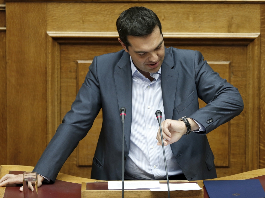 Greek Prime Minister Alexis Tsipras looks at his watch as he speaks to a marathon parliamentary session in Athens on Friday. A bitterly divided parliament approved a draft bailout agreement with international lenders