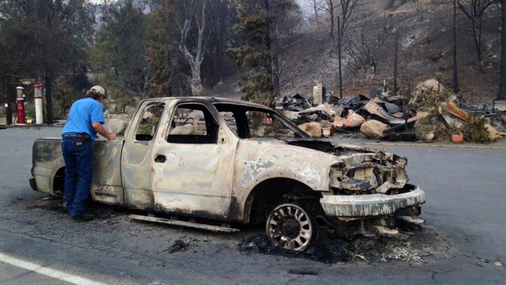 A man checks whats left of a pickup truck