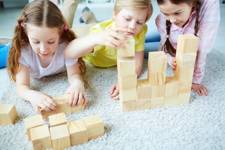 Two girls and one boy playing with wooden blocks