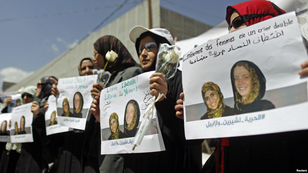 FILE- Women hold posters bearing likenesses of Frenchwoman Isabelle Prime and her Yemeni translator Shereen Makawi during a protest to demand their release in San'aa Yemen