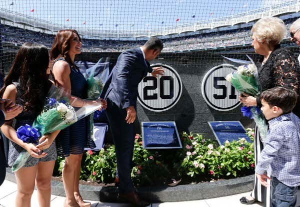 Accompanied by family members former New York Yankees catcher Jorge Posada touches a plaque with his jersey number on a wall in Monument Park during a ceremony retiring his number before a baseball game against the Cleveland Indians, Aug 22 2