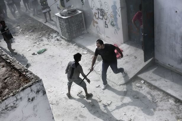 A policeman hits a migrant with a truncheon during a registration procedure