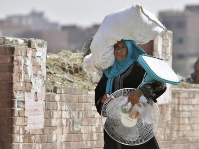 An Egyptian farmer carries an electric fan as she walks through a Cairo street on Tuesday. Egyptian health authorities say at least 40 people have died in the last two days amid a scorching heatwave hitting the country