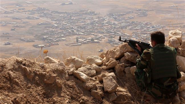 An Iraqi Kurdish Peshmerga fighter monitors his surrounding from the top of Mount Zardak about 25 kilometers east of Mosul