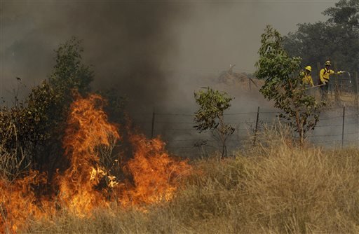 A fire crew works a back fire along Morgan Valley Road near Lower Lake Calif. Wednesday Aug. 12 2015. Erratic winds fanned a wildfire burning through rugged hills in Northern California on Wednesday pushing the flames across two counties and chasing