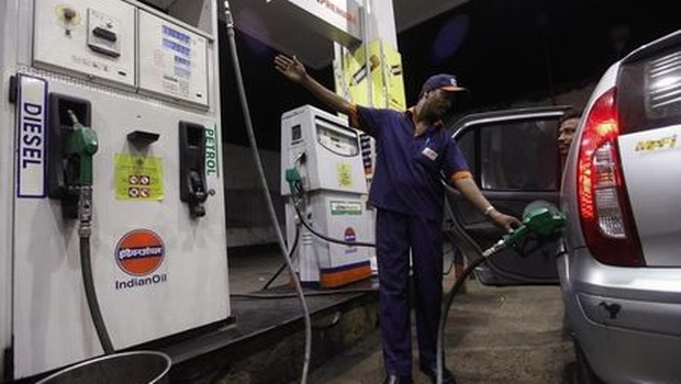 A worker fills a car with petrol as he gestures towards the fuel barometer for the passenger to check at a fuel station in Kolkata