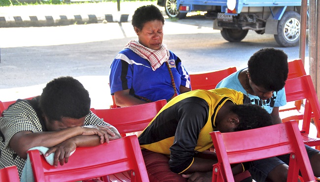 Relatives of passengers on the missing Trigana Air Service flight sit at Sentani airport in Jayapura Papua province Indonesia Monday Aug. 17 2015. Rescue officials spotted an Indonesian airliner that went missing on Sunday in the country's mount