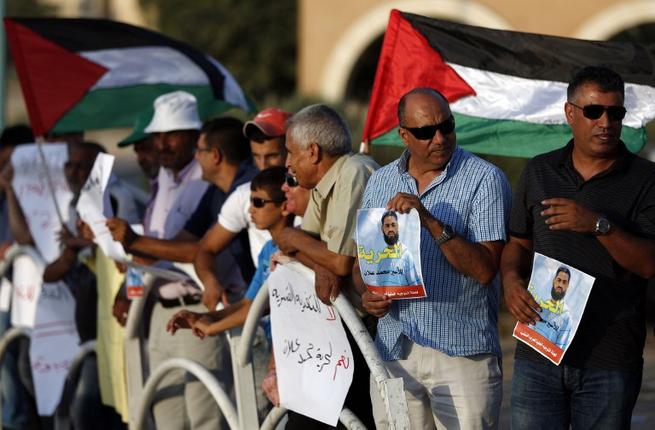 Arab-Israeli protesters wave Palestinian flags and hold posters of Mohammed Allan a Palestinian prisoner who is on a long-term hunger strike during a rally calling for his release in the southern Israeli Bedouin city of Rahat