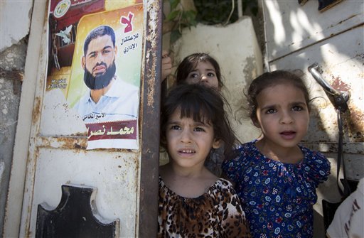 Palestinian girls from left Ghofran Lane and Mary stand next to a poster showing their uncle Mohammed Allan at the family house in the village of Einabus near the West Bank city of Nablus. Allan spent