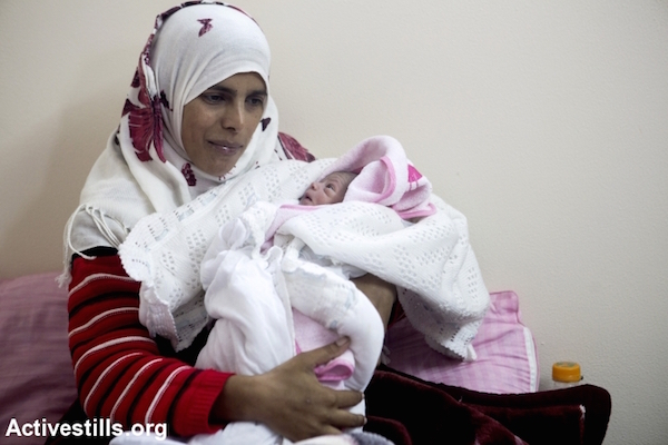 Tahrir Najjar with her two-day-daughter Sundos in the room where she stays in a newly-established camp with metal caravan shelters for displaced people in the village of Khuza'a eastern Gaza Strip