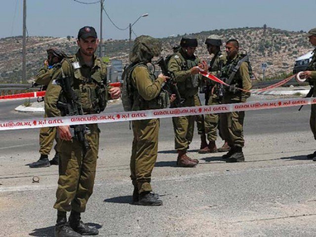 Israeli security forces stand in a security perimeter where a young Palestinian man was shot and wounded by Israeli troops after he stabbed a soldier