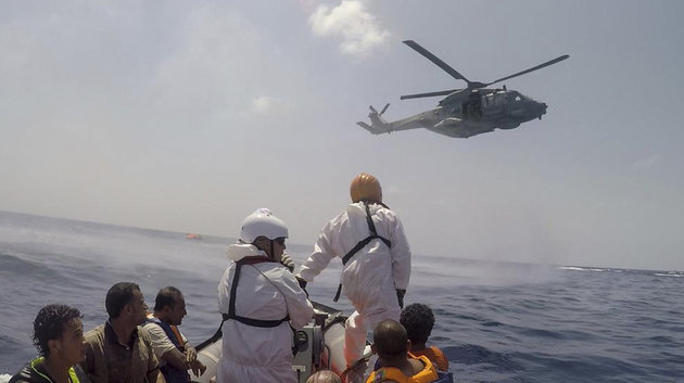 A helicopter and a rescue boat work on the scene of a sinking fishing boat crowded with migrants in the Mediterranean sea off Libya Wednesday Aug. 5 2015