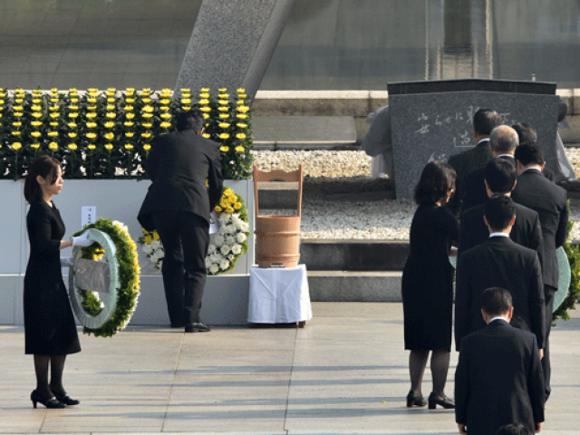 Japanese Prime Minister Shinzo Abe offers a wreath of flowers at the memorial cenotaph for victims of a 1945 atomic bombing during a memorial ceremony to mark the 70th anniversary at the Hiroshima Peace Memorial Park in western Japan on August 6