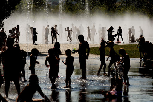 Children cool off as they play under a fountain next to the Manzanares river