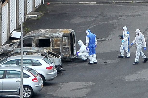 Army bomb squad seal off a road inside Palace Army Barracks in Northern Ireland while forensic experts move in to examine a burnt out vehicle after an explosion  fire