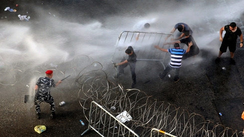 Lebanese activists right remove barriers as riot police spray them with water cannons during a protest against the ongoing trash crisis