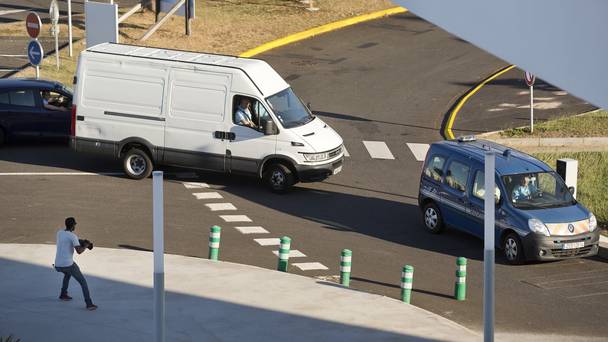 A white van carrying the wing part that was washed up on a beach approaches a cargo hangar at the Roland Garros Airport in Sainte-Marie on the north coast of the Indian Ocean island of Reunion