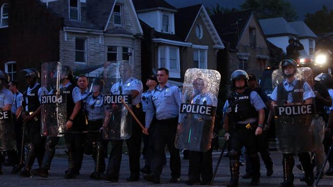 Police in riot gear stand guard as protesters gather on August 19 in St. Louis