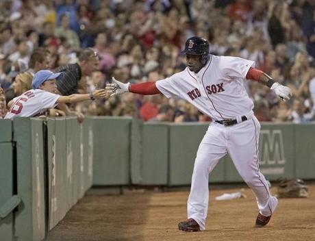 Boston MA 7/27/15 Boston Red Sox Rusney Castillo reaching to high five a fan afeter scoring on Mookie Betts infield single against the Chicago White Sox during fourth inning action at Fenway Park on Monday