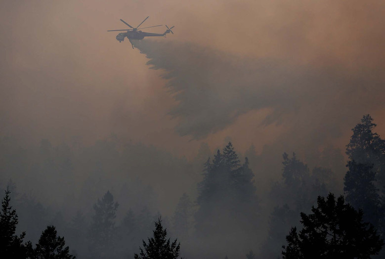 A helicopter drops a load of water Sunday on the First Creek Fire