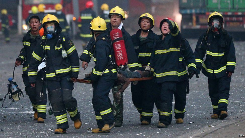 Firemen carry a body at the scene of two powerful explosions in the Chinese city of Tianjin