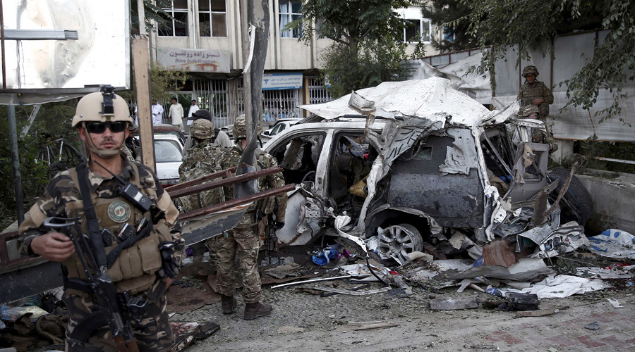 Afghan security personnel keeps watch next to a damaged car belonging to foreigners after a bomb blast in Kabul Afghanistan