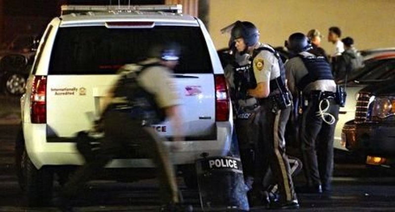 A police officer runs to take cover after shots were fired in a police-officer involved shooting in Ferguson Missouri