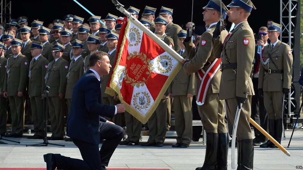 Polish President Andrzej Duda kneels before a military flag before taking over authority Polish Armed Forces as the Polish Armed forces during the ceremony at Pilsudski Square in Warsaw Poland