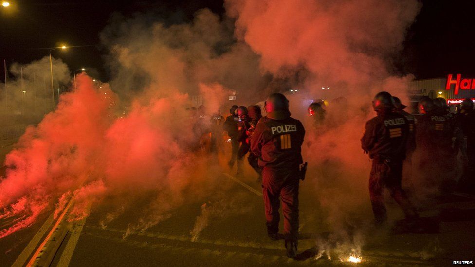 Police walk between flares thrown by right-wing protesters who are against bringing asylum seekers to an accommodation facility in Heidenau Germany